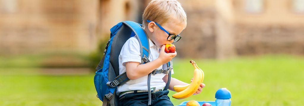A young boy at school eating an apple
