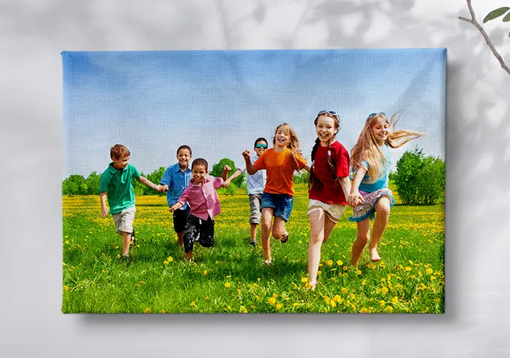 canvas print of a group of joyful young boys and girls running on grass field with joined hands