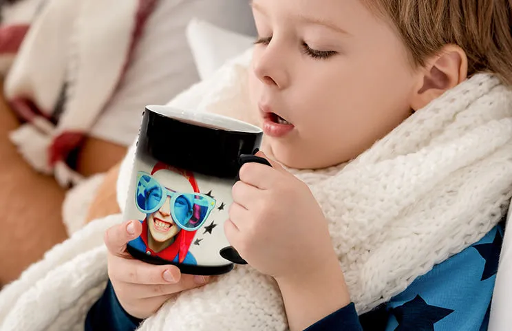 Young boy holding custom designed magic mug with photo of himself on