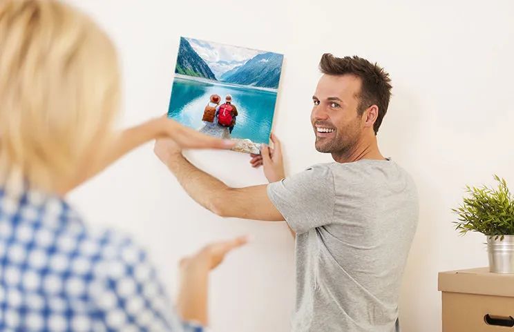Man and woman putting up a photo canvas with a holiday photo on