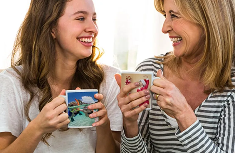 Mom and daughter holding custom designed photo mugs with family photos