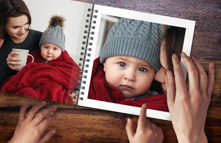 A spiral book open with two photos of a baby